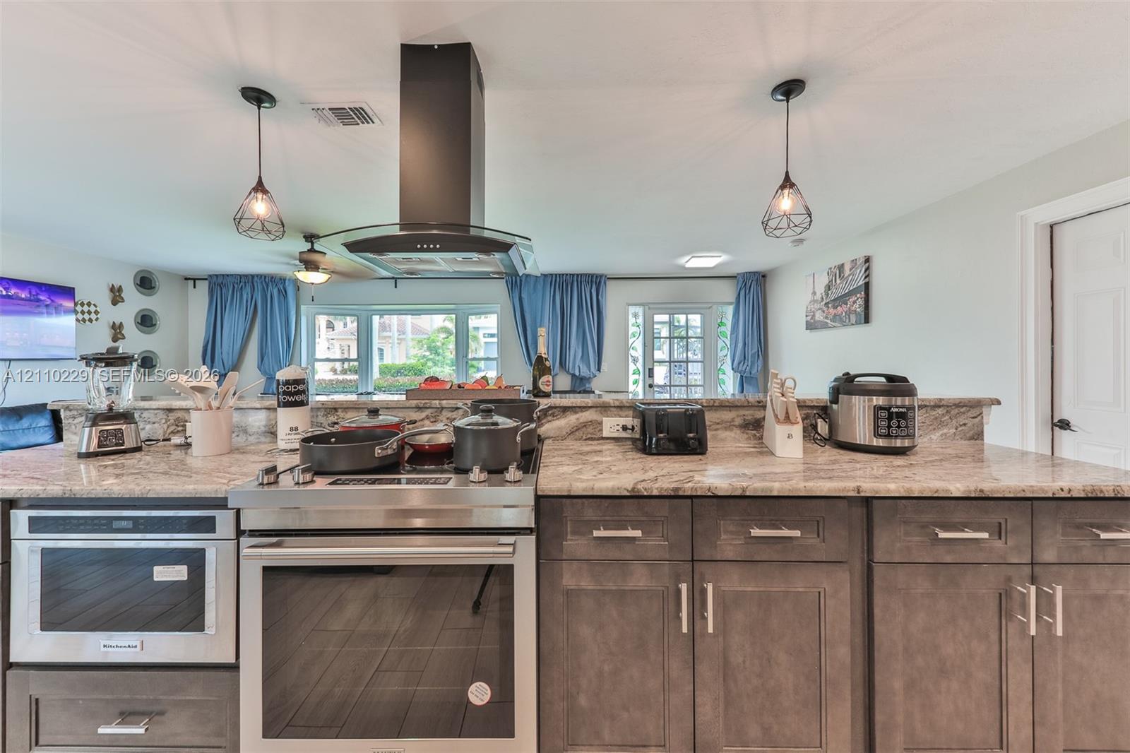 Kitchen featuring a stainless steel range, built-in microwave, stone-surface countertops, dark wood-finish cabinetry, and a chimney-style range hood