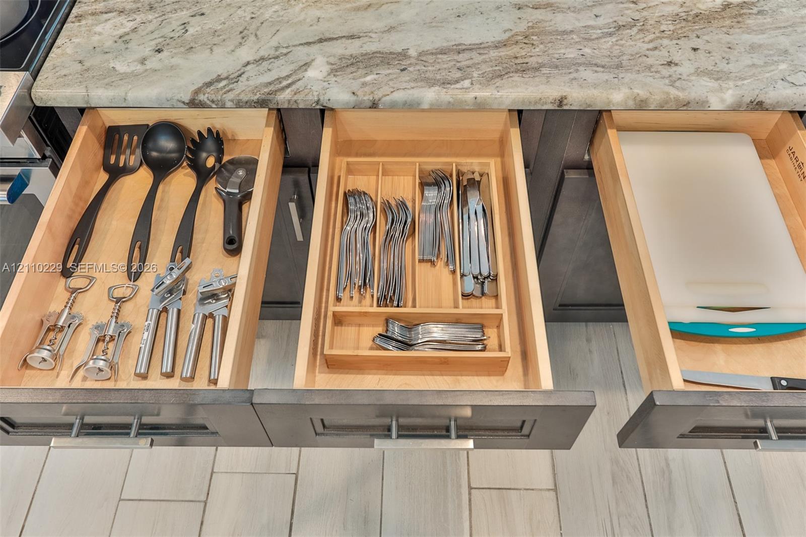 Custom cabinetry featuring soft-close wooden drawers, built-in drawer organizers, and natural stone countertops