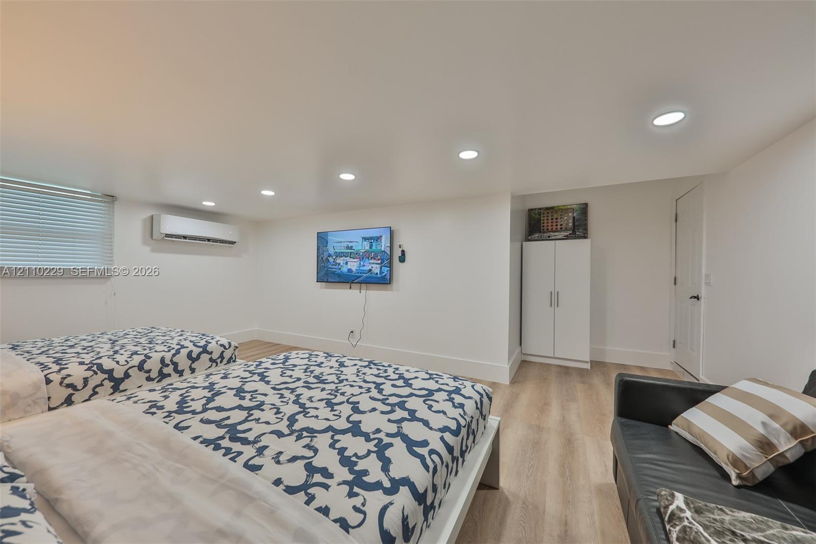 Interior space featuring wood-finish flooring, recessed lighting, and a wall-mounted ductless climate control unit