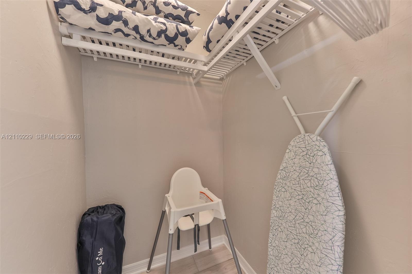 Storage area featuring white ventilated shelving and light-toned tile flooring