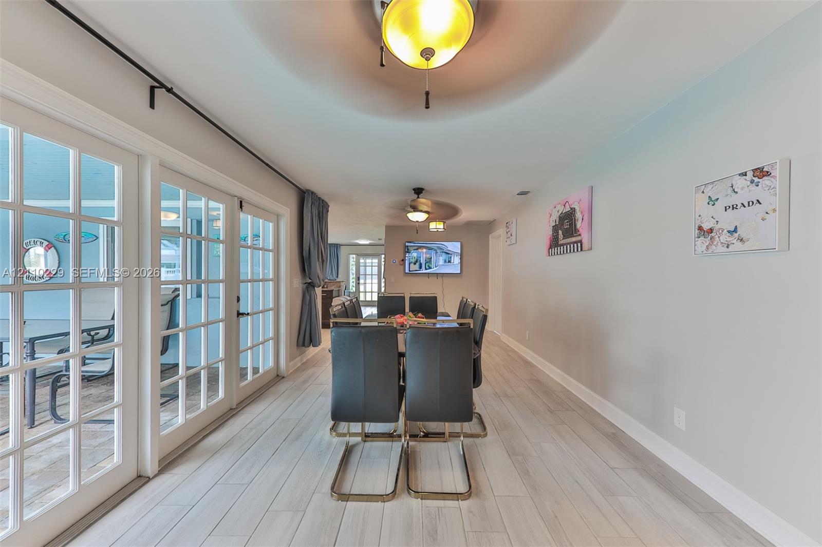 Multi-panel glass doors, neutral wood-finish flooring, recessed ceiling lighting, and dual ceiling fans