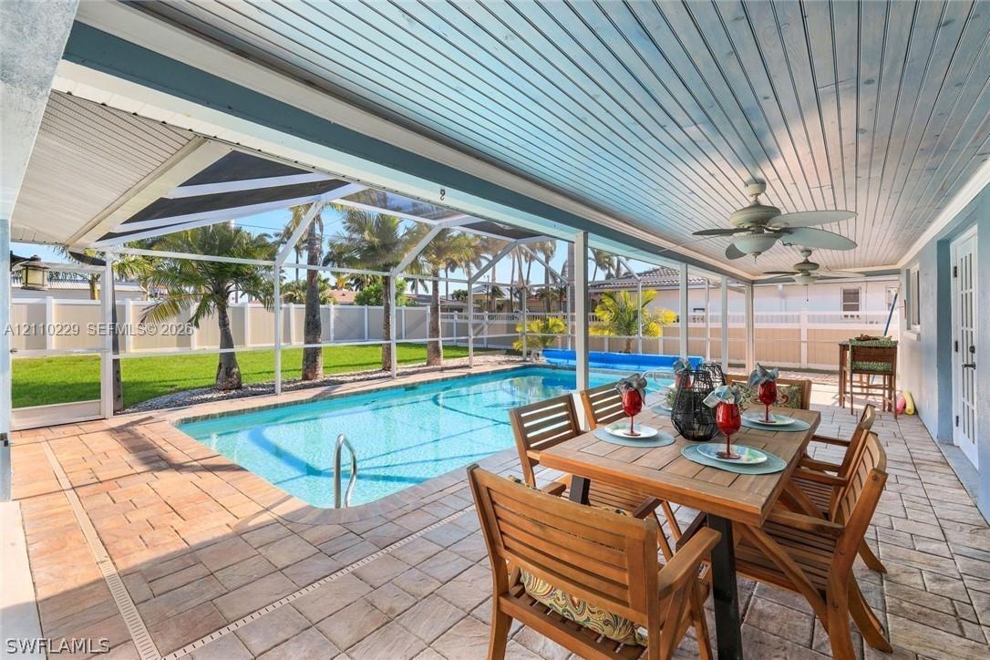 Covered lanai featuring a painted wood-plank ceiling with dual ceiling fans, paver patio, screened enclosure, and an in-ground swimming pool