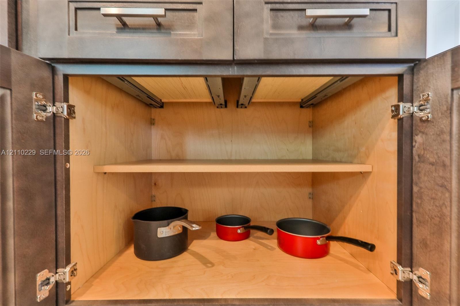 Dark-stained cabinetry featuring shaker-style doors, horizontal brushed-nickel hardware, full-extension interior pull-out shelving, and adjustable shelving