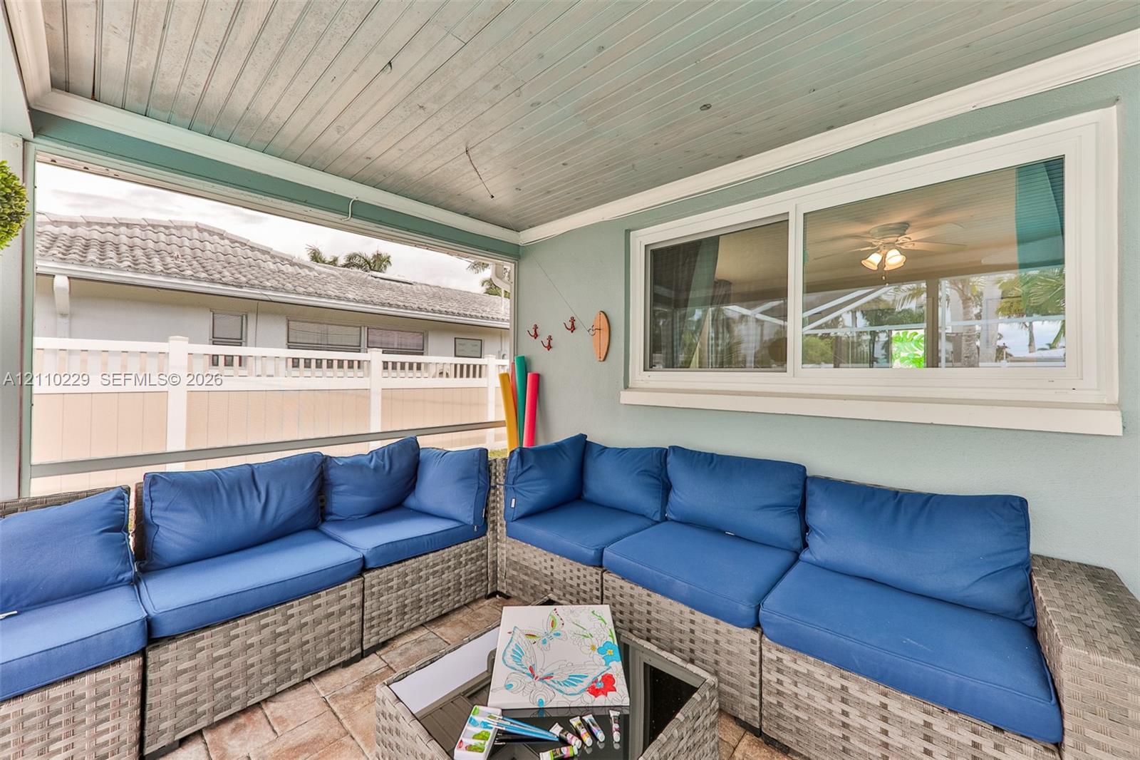 Screened-in porch featuring a tongue-and-groove wood-finish ceiling, paver flooring, sliding glass window, and vinyl privacy fencing