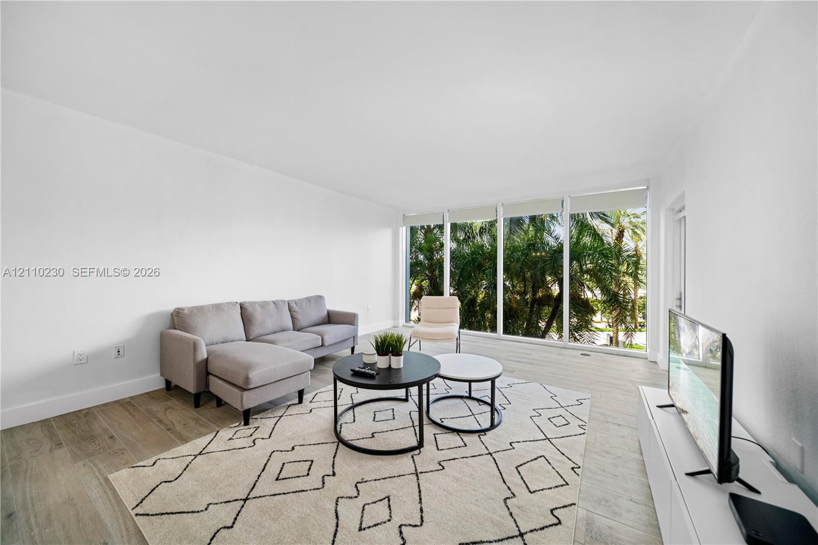 Expansive living area featuring floor-to-ceiling windows, wood-finish flooring, and neutral wall tones