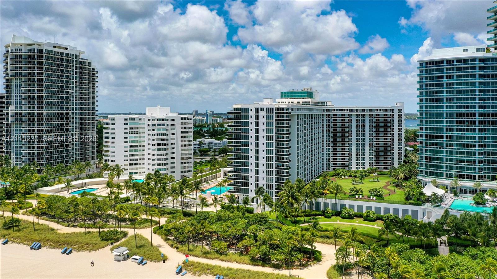 High-rise residential towers featuring private swimming pools, landscaped lawn areas, and direct sandy beach access
