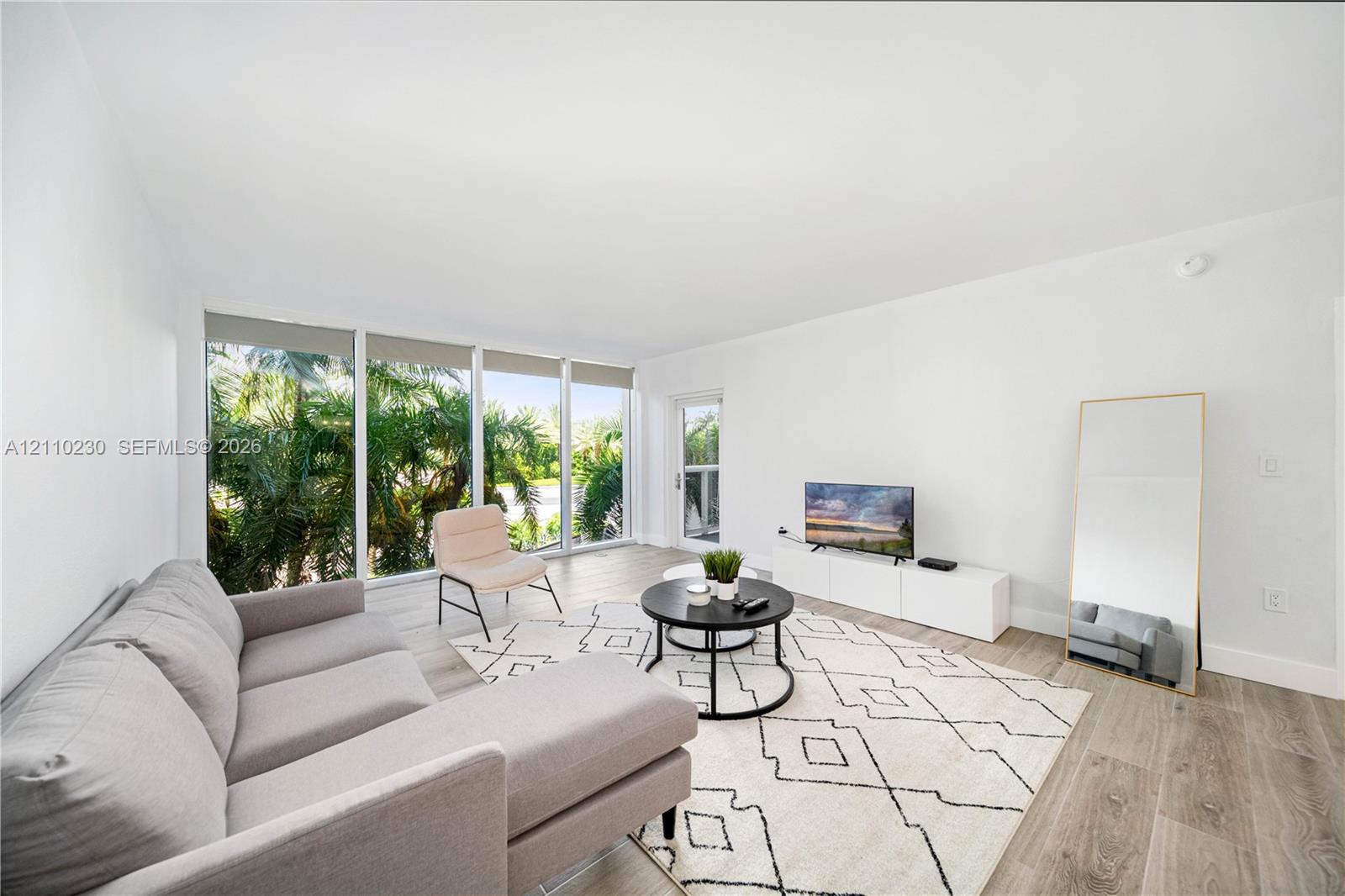Living area featuring wood-finish flooring, floor-to-ceiling windows, and glass-paneled entry door