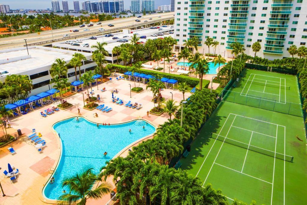 Resort-style amenities featuring dual outdoor swimming pools, two hard-surface tennis courts, and landscaped grounds with mature palm trees Resort-style amenities featuring dual outdoor swimming pools, two hard-surface tennis courts, and landscaped grounds with mature palm trees