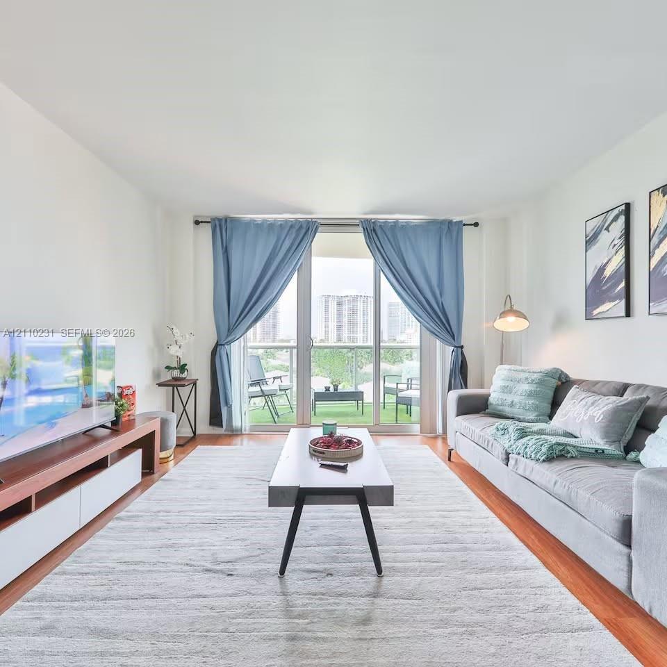 Living area featuring wood-finish flooring, floor-to-ceiling glass sliding doors, and a private balcony Living area featuring wood-finish flooring, floor-to-ceiling glass sliding doors, and a private balcony