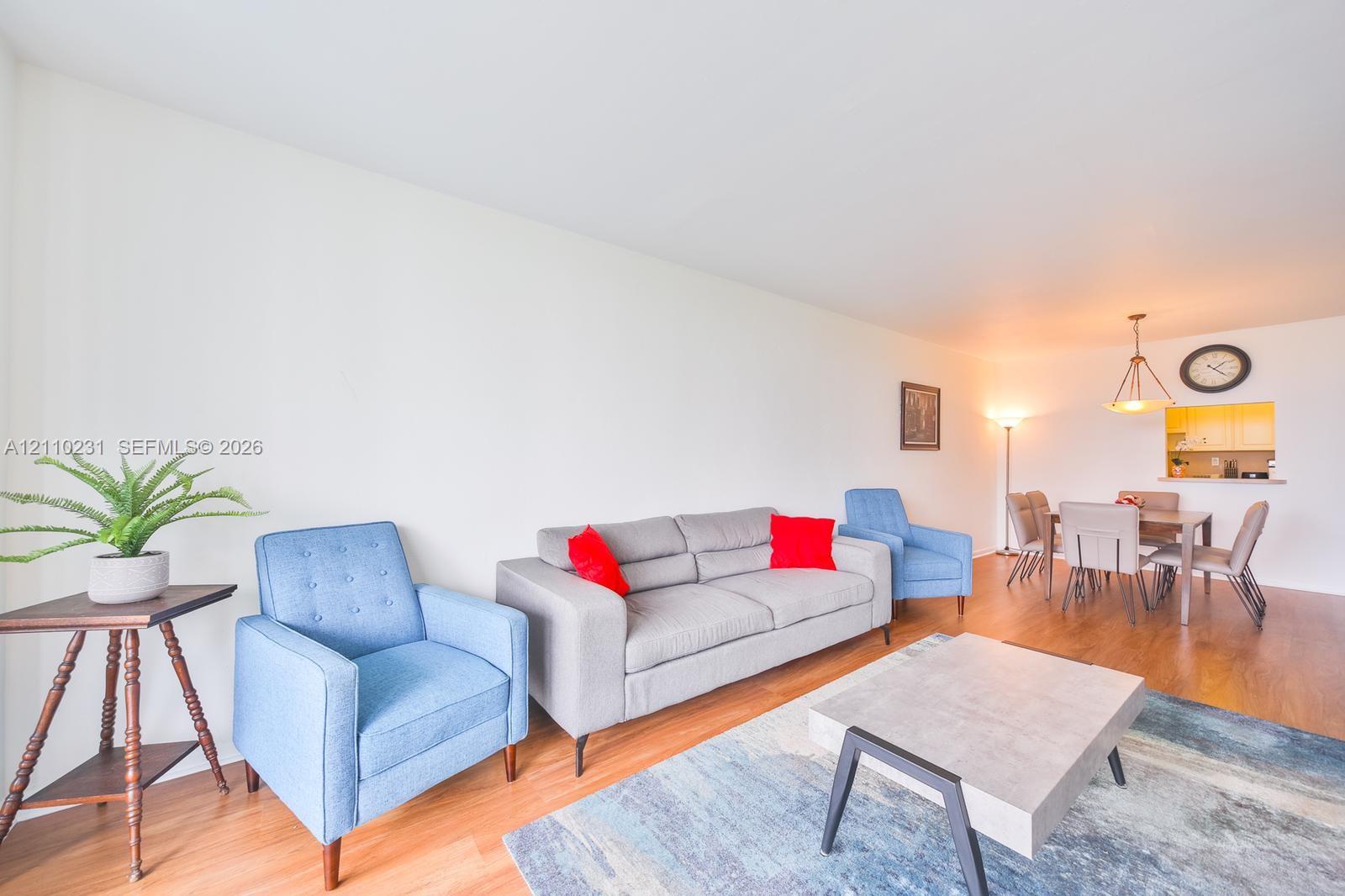 Open-concept interior featuring wood-finish flooring, a kitchen passthrough, and a tiered pendant light fixture
