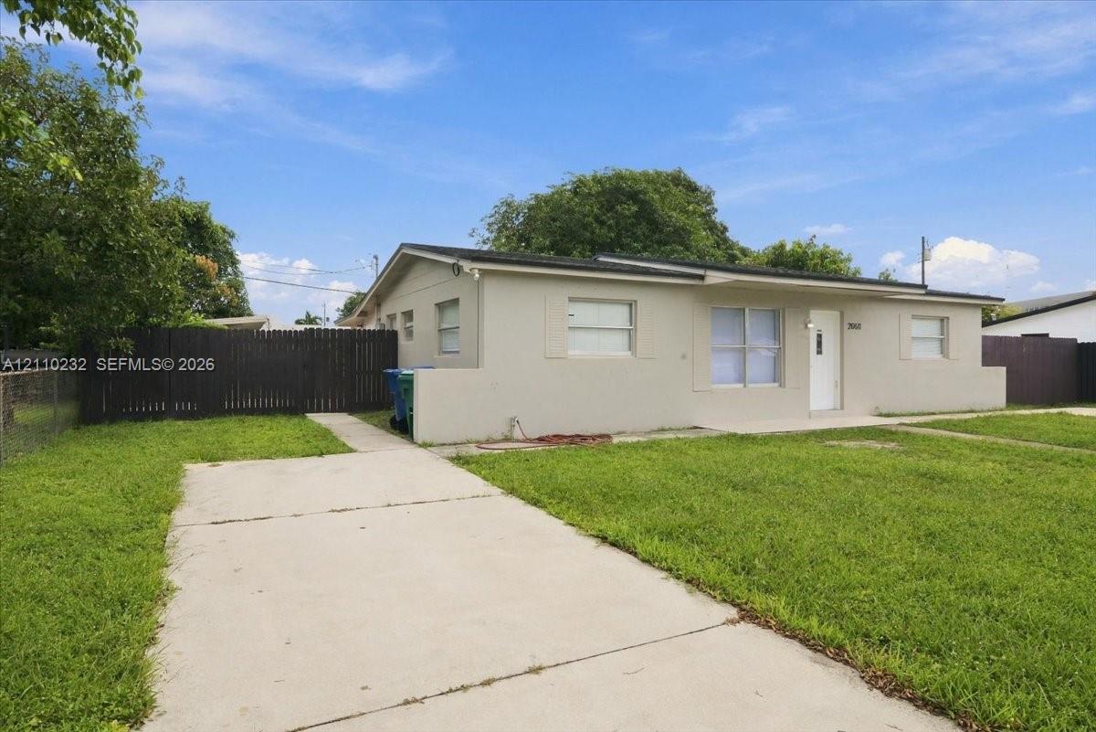 Single-story residence featuring a concrete exterior, covered entry, concrete driveway, and a wood privacy fence