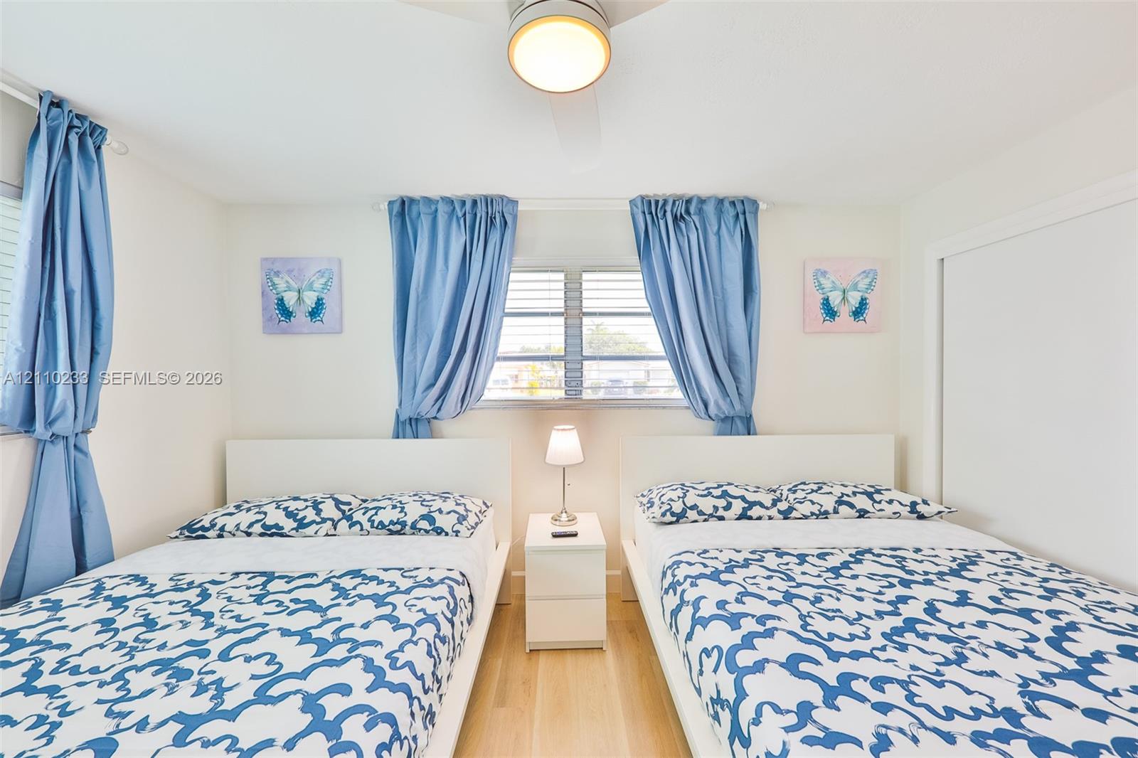 Bedroom featuring wood-finish flooring, louvered windows, and a ceiling-mounted light fixture