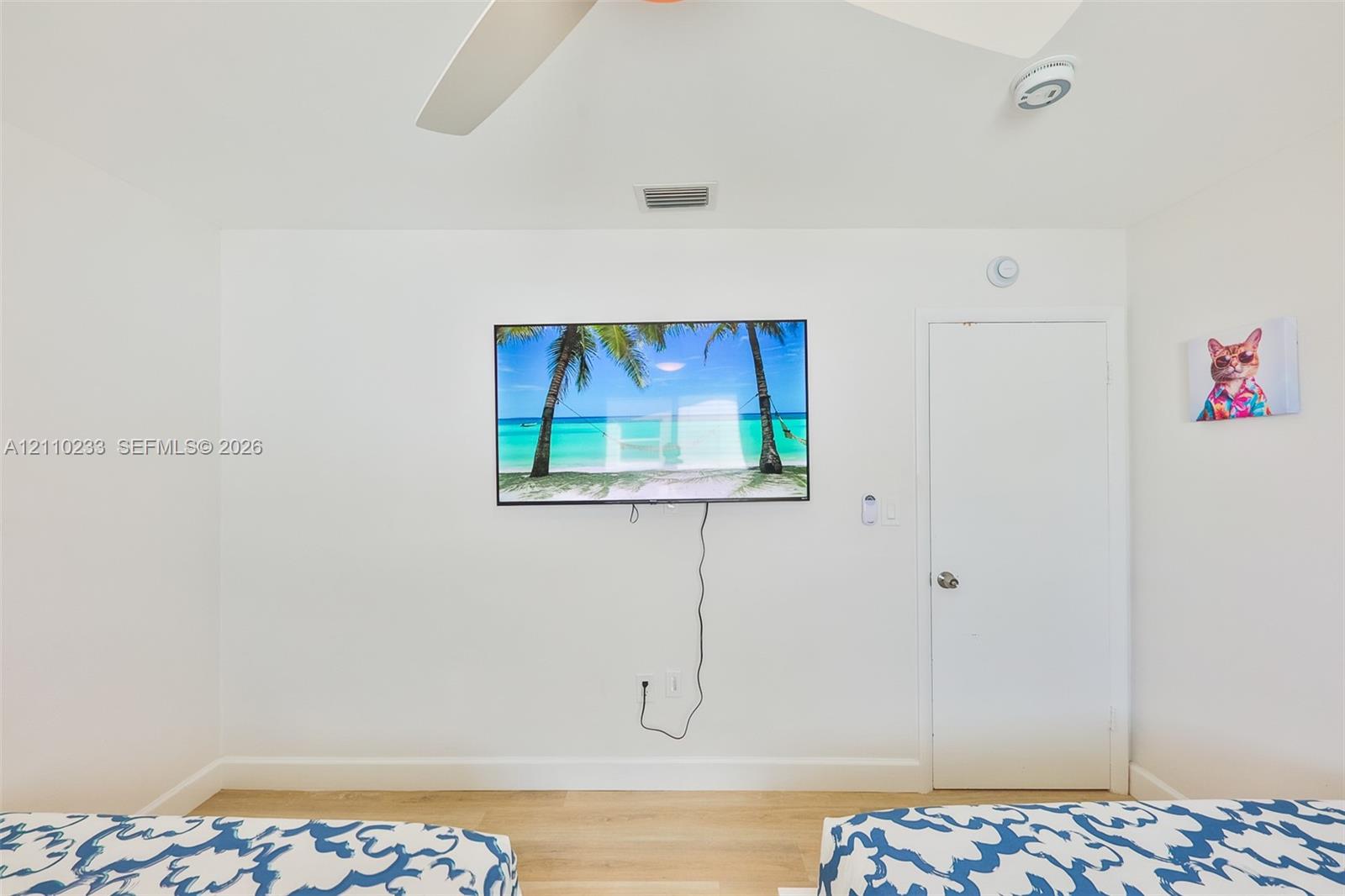 Neutral-toned interior featuring light-finished flooring, a ceiling fan, and a wall-mounted flat-panel television