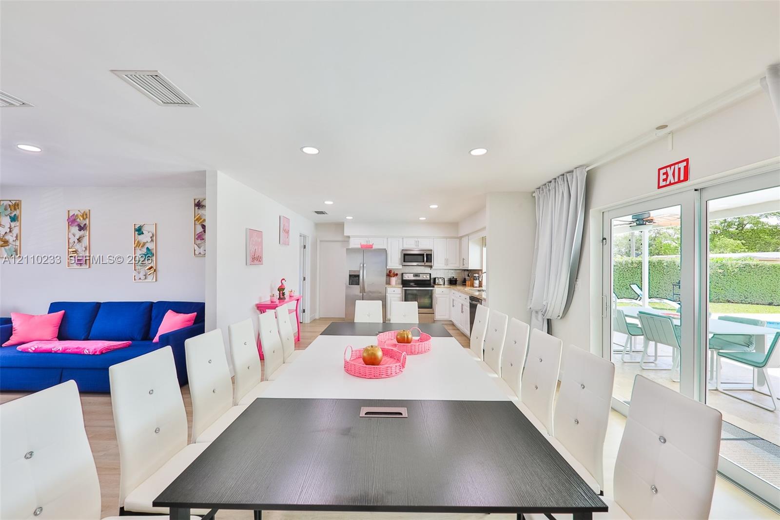Open-concept interior featuring recessed lighting, light-toned flooring, and white kitchen cabinetry with stainless steel appliances
