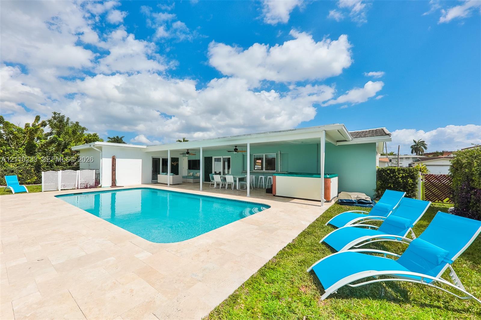 In-ground swimming pool with stone-tiled patio, expansive covered outdoor terrace, and built-in spa