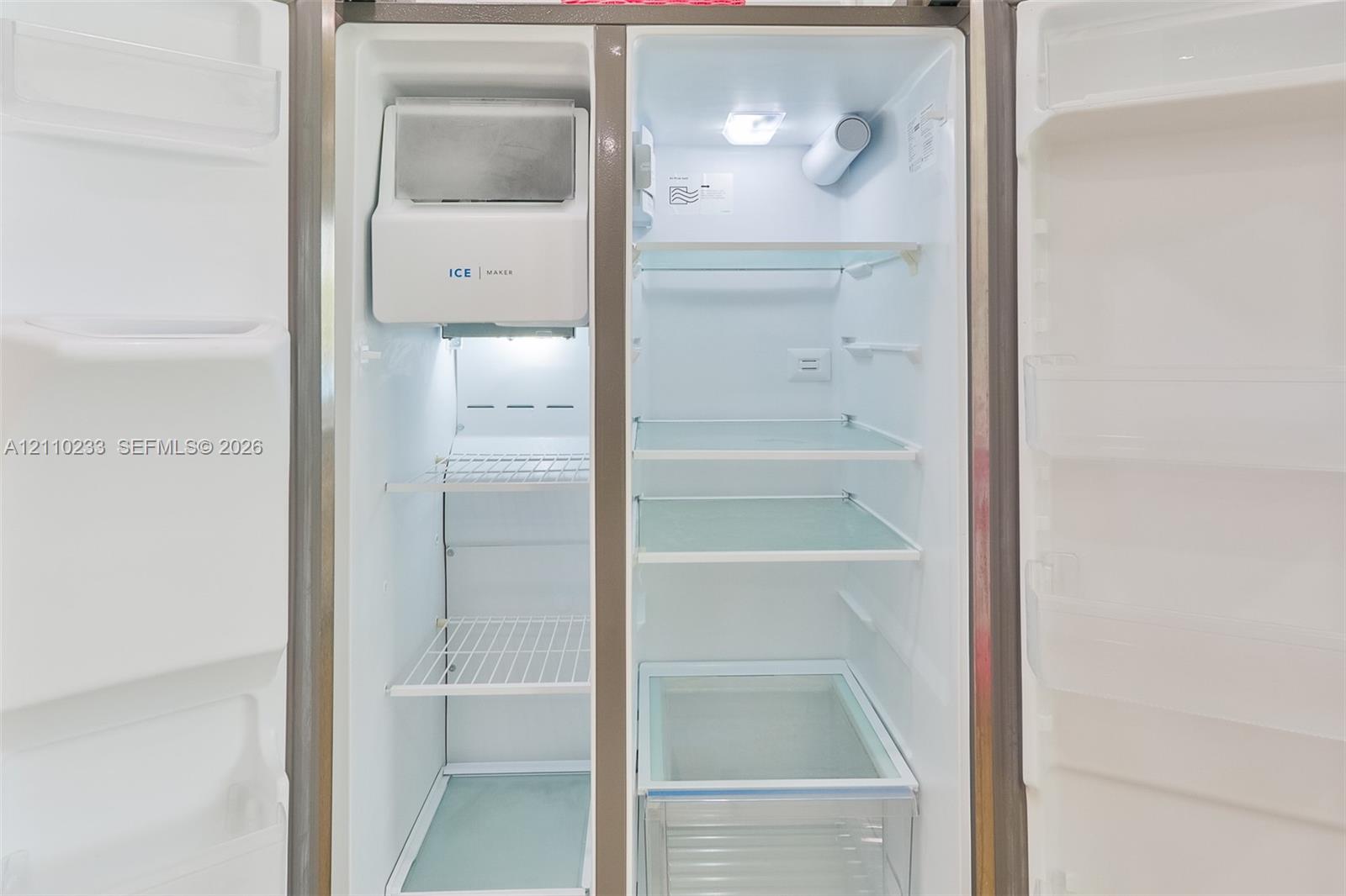 Side-by-side refrigerator featuring adjustable glass shelving, an integrated ice and water dispenser, and a dedicated crisper drawer