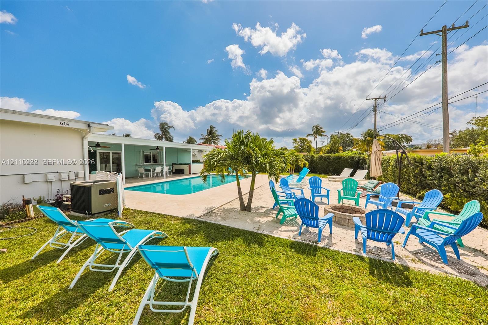 Outdoor living space featuring an inground swimming pool, concrete patio, circular stone fire pit, and lawn area