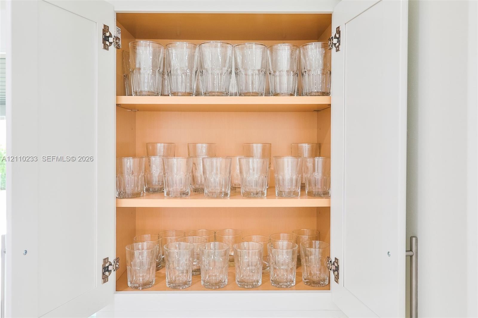 Shaker-style cabinet doors with a matte finish, concealed hinges, and stainless steel bar pulls, featuring adjustable wood-toned shelving