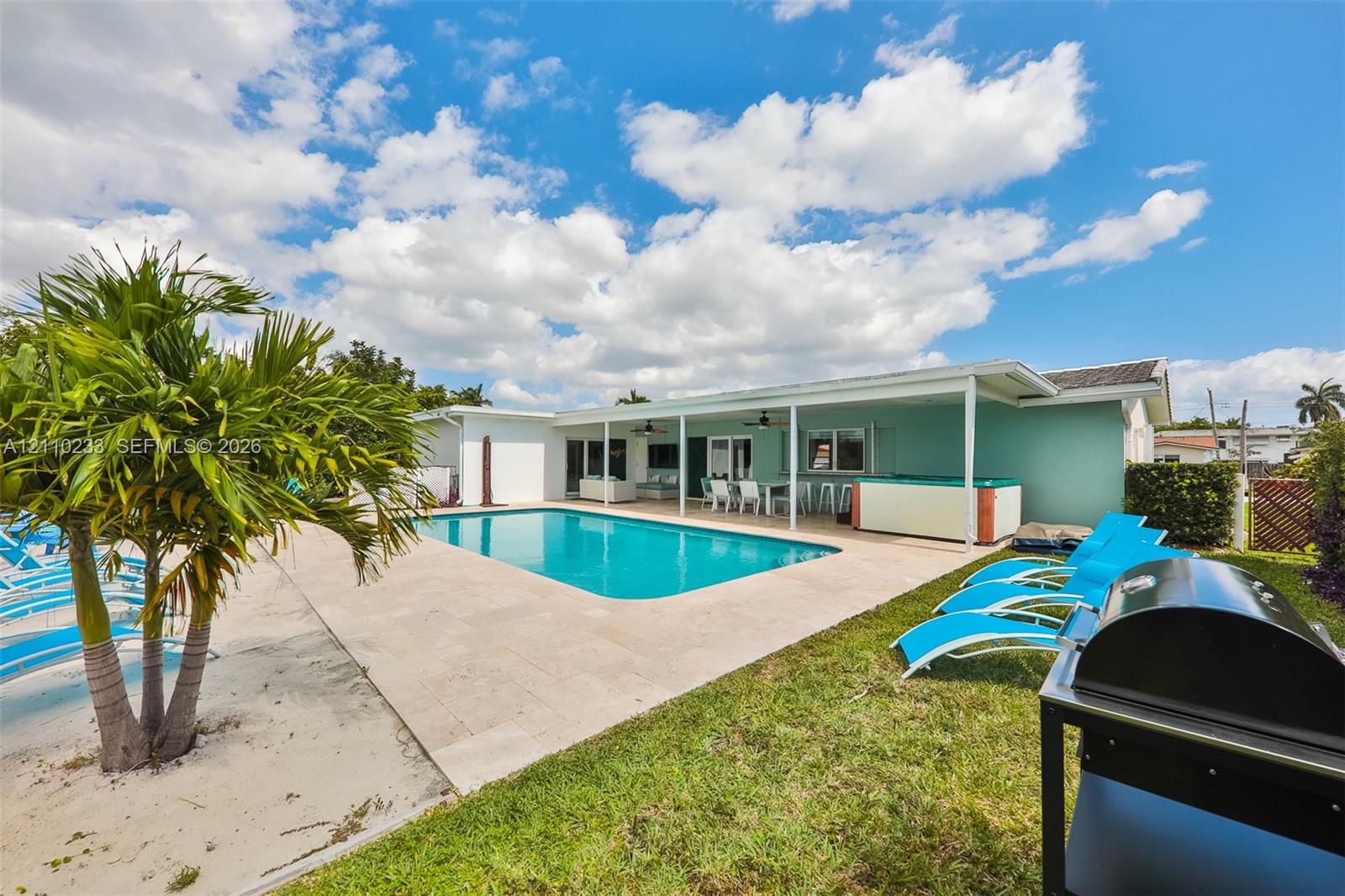 In-ground swimming pool with stone paver decking, covered patio, and attached hot tub