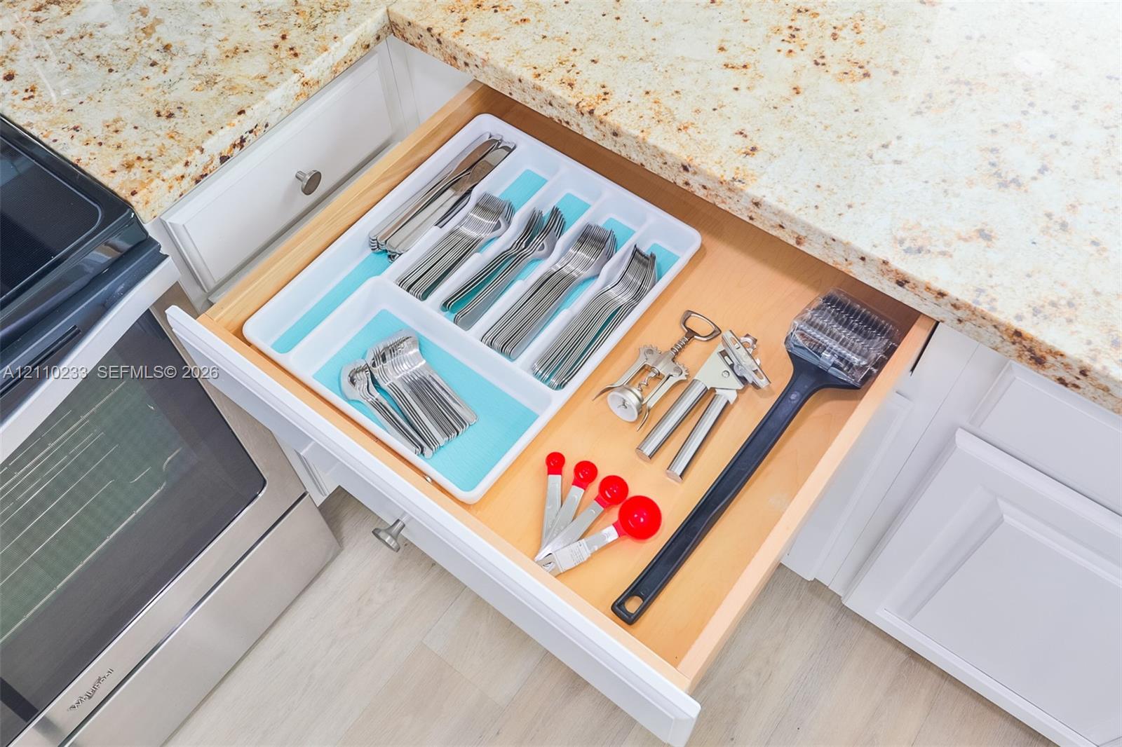 Custom-fitted drawer cabinetry featuring natural wood finishes, paired with durable stone-finish countertops and white shaker-style cabinetry