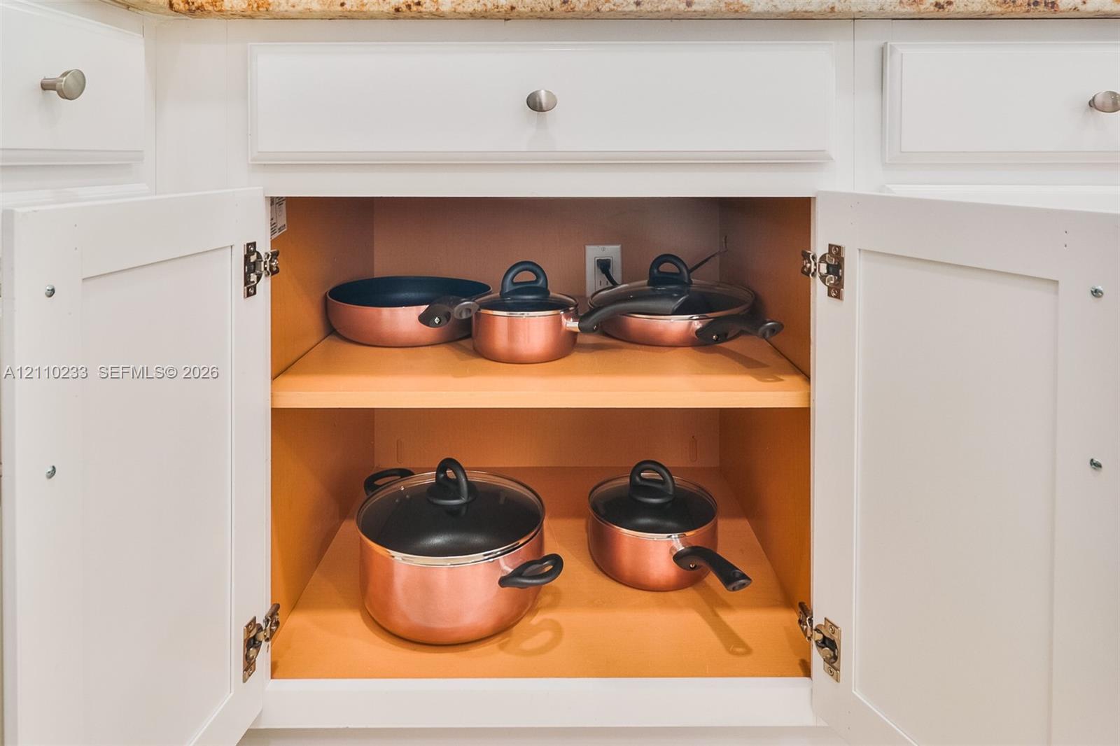Shaker-style cabinetry featuring white finish, silver-tone hardware, and adjustable shelving