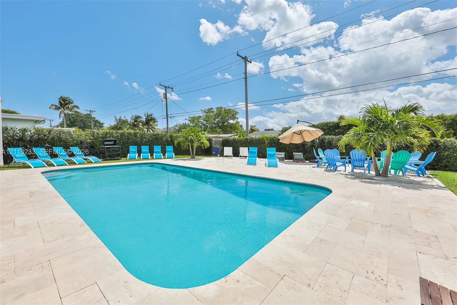 In-ground swimming pool with stone-finish patio surround and perimeter greenery