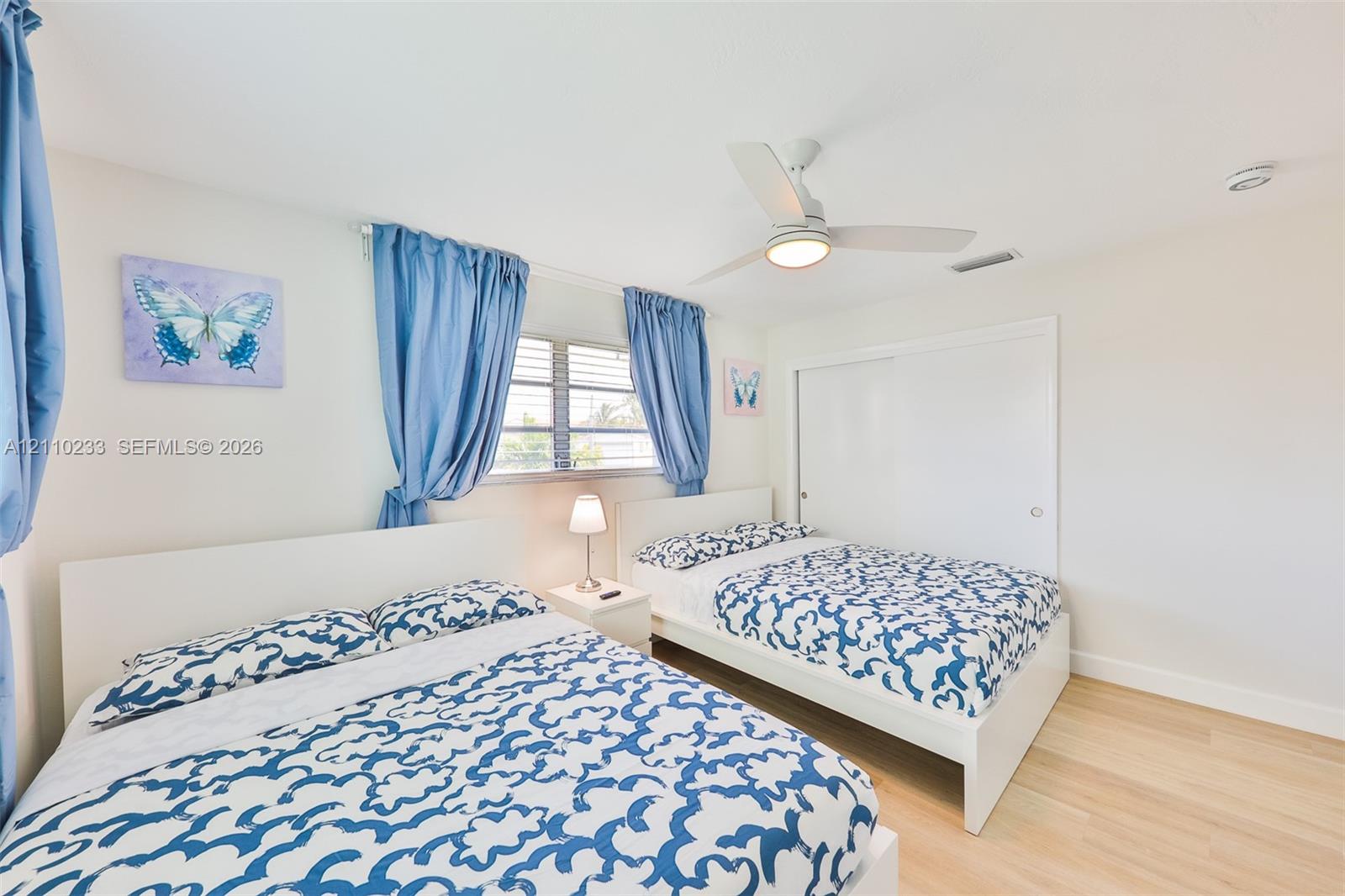 Wood-finish flooring, white sliding closet doors, and a ceiling-mounted fan with integrated lighting