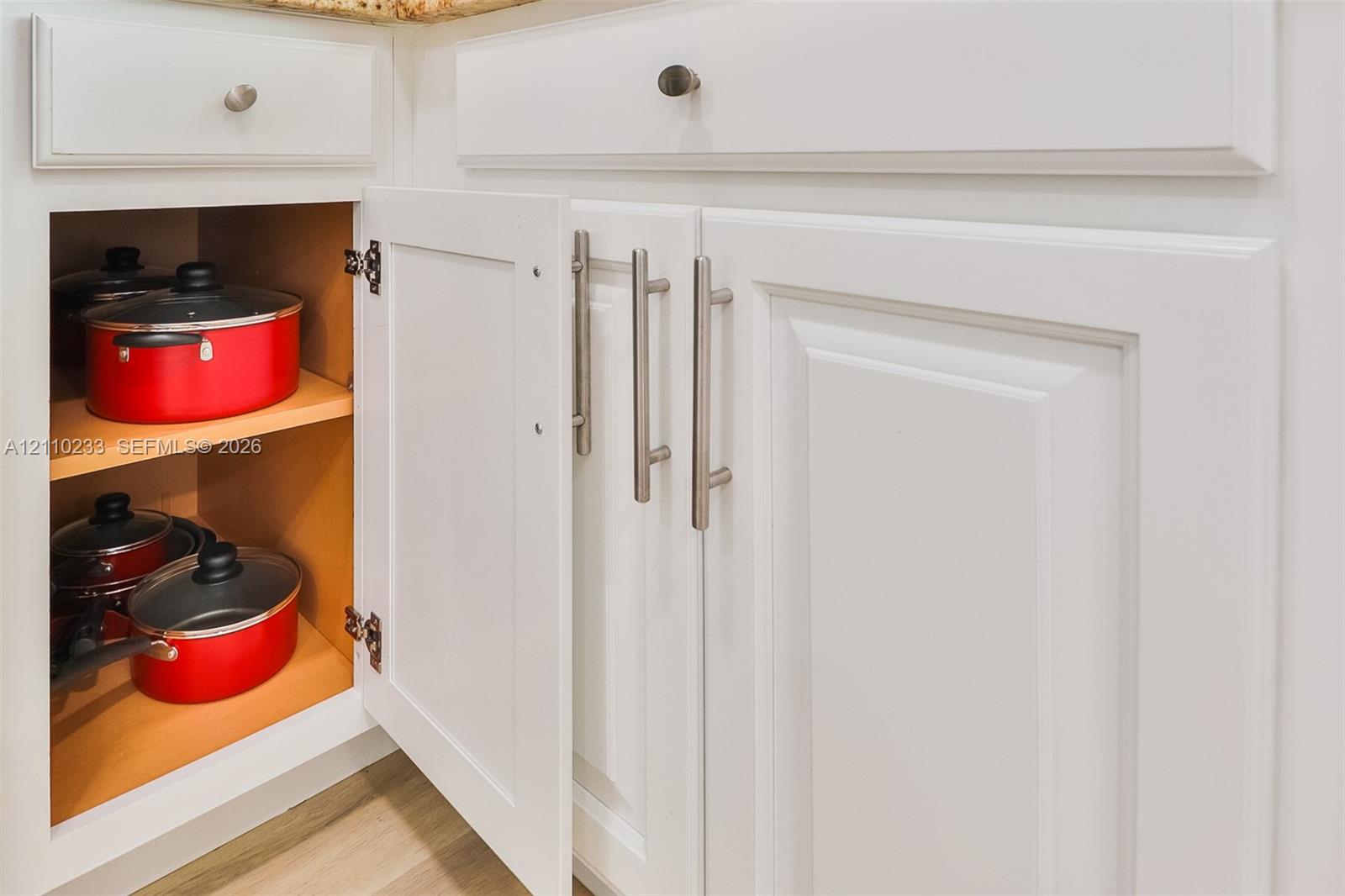 White shaker-style cabinetry featuring satin nickel bar pulls, adjustable interior shelving, and soft-close hinges