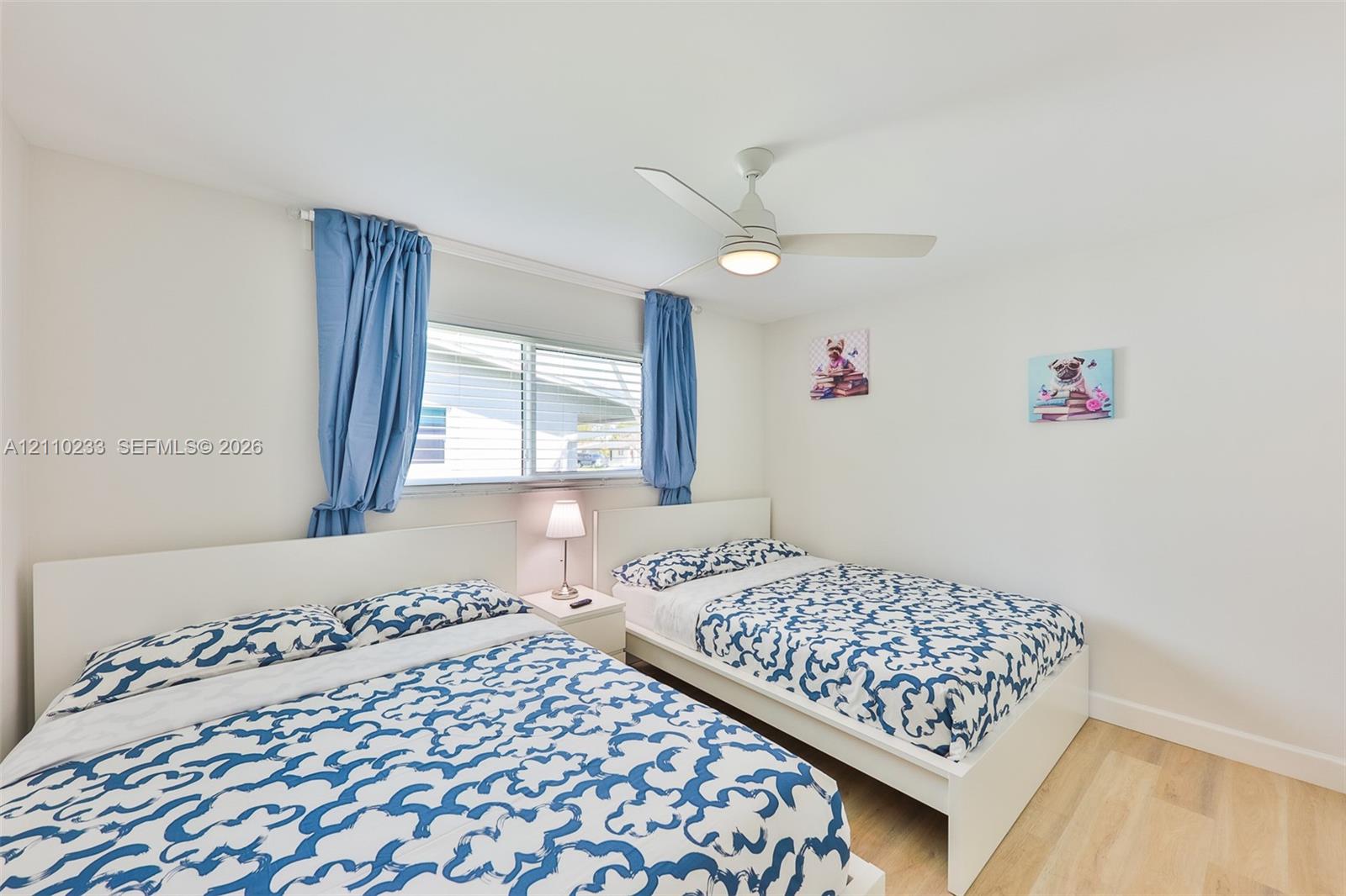 Bright room featuring wood-finish flooring, a neutral color palette, and a central ceiling fan with an integrated light fixture