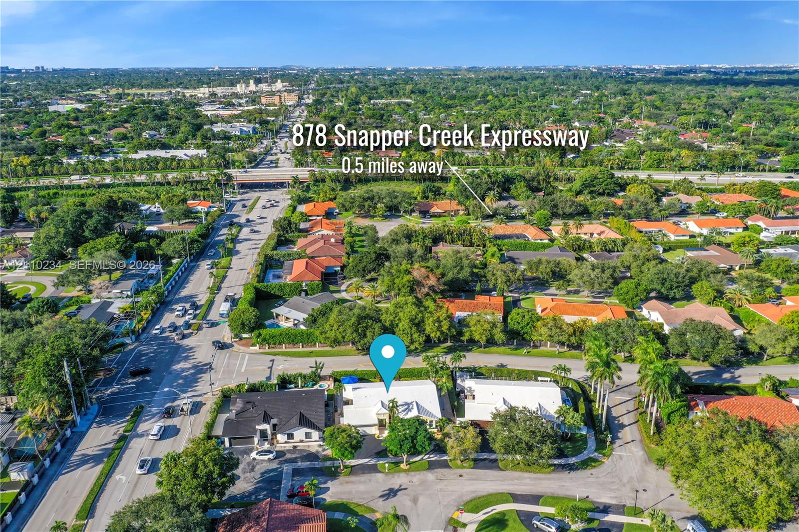 Aerial perspective of property featuring mature canopy trees, paved circular driveway, and white roofing systems