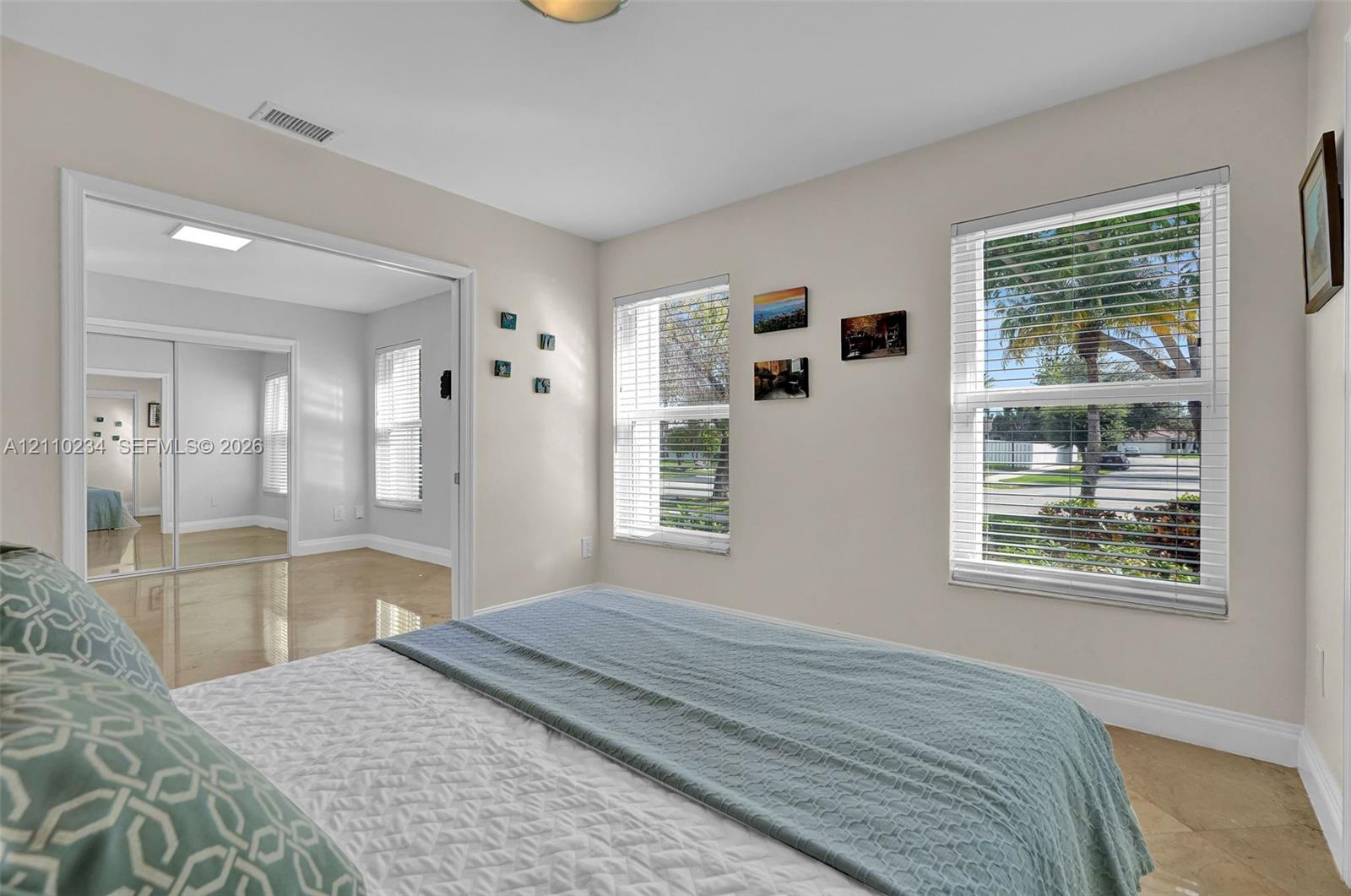 Neutral-toned interior featuring oversized tile flooring, large dual-pane windows with integrated blinds, and mirrored closet doors