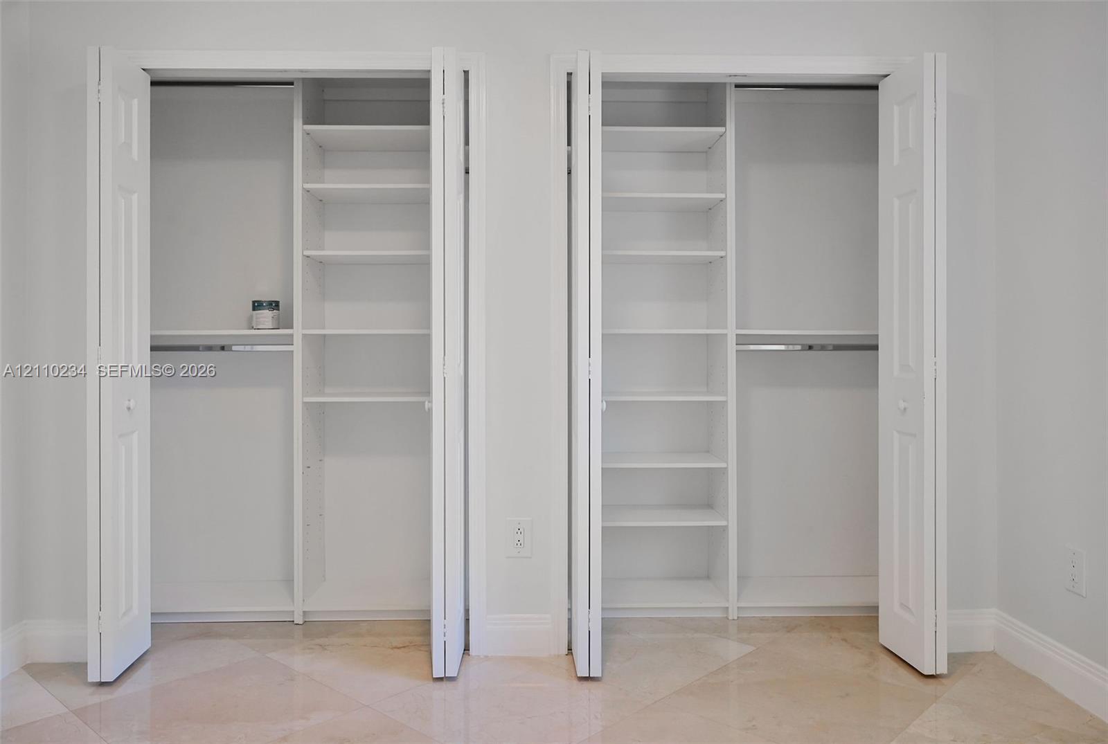 Dual closets featuring white bi-fold doors, built-in shelving units, and integrated clothing rods