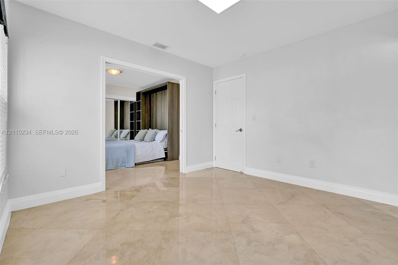 Large-format neutral tile flooring, smooth ceilings, and white interior doors