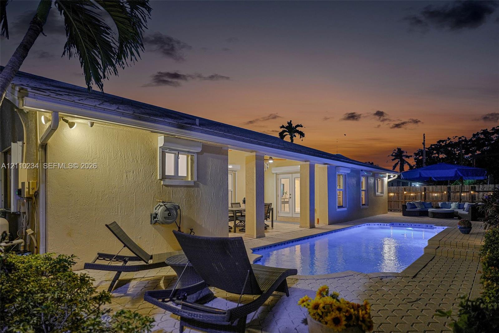 Outdoor space featuring a rectangular in-ground swimming pool, paver patio, covered lanai, and exterior wall-mounted lighting