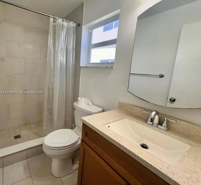 Bathroom featuring a vanity with a light-toned solid surface countertop and integrated basin, a stall shower with tiled walls, large-format floor tile, and a wall-mounted mirrored cabinet