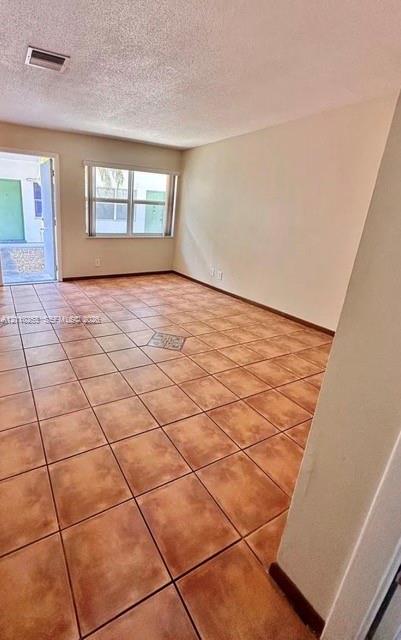 Interior space featuring ceramic tile flooring, neutral wall tones, a large window, and an exterior door