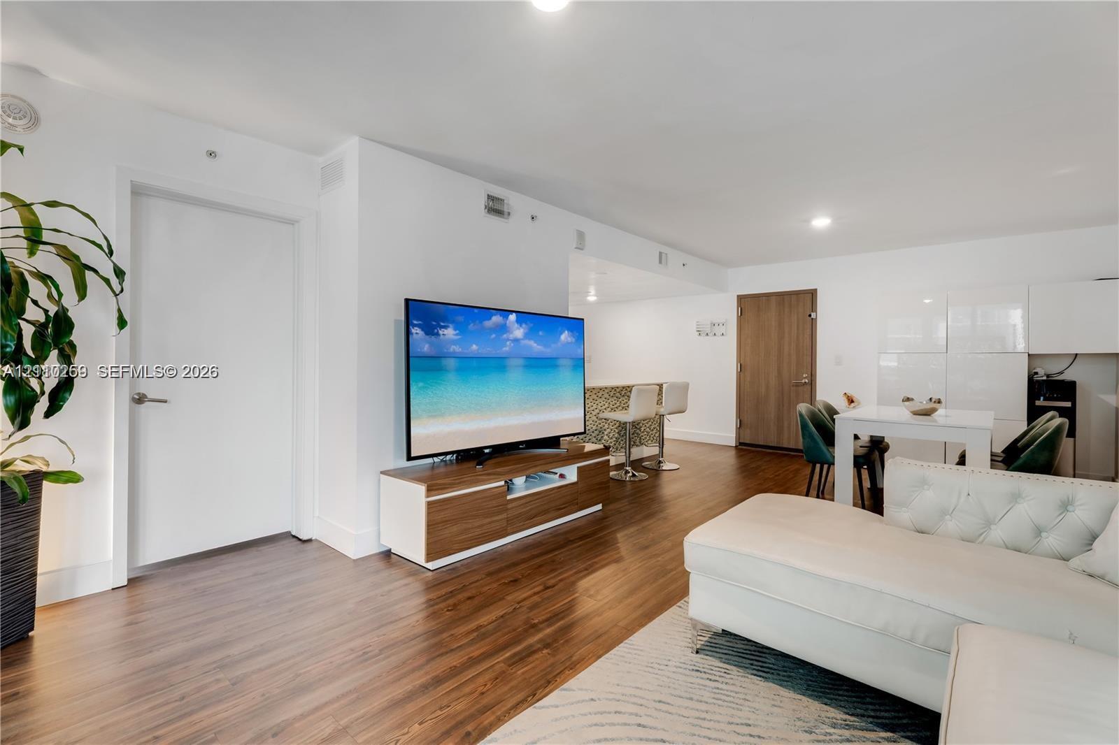 Open-concept interior featuring wood-finish flooring, recessed lighting, and a kitchen peninsula with a tiled front