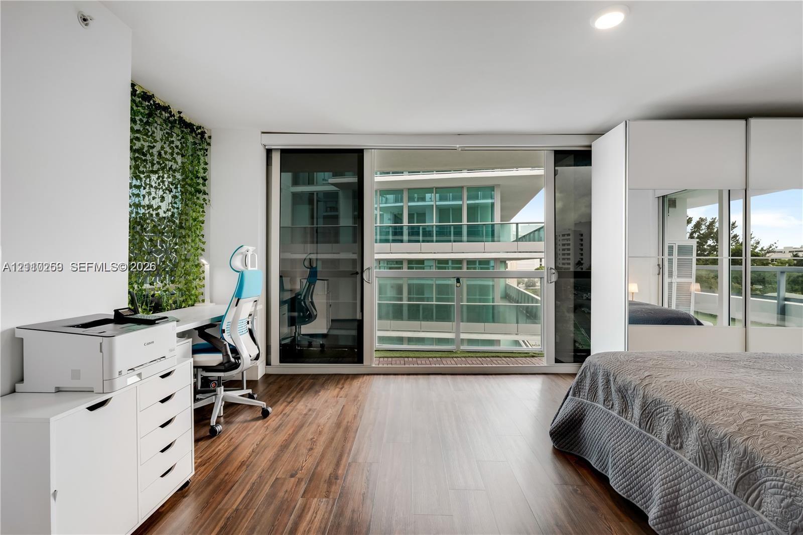 Wood-finish flooring, sliding glass balcony doors, built-in floor-to-ceiling cabinetry, recessed lighting, and integrated wall shelving