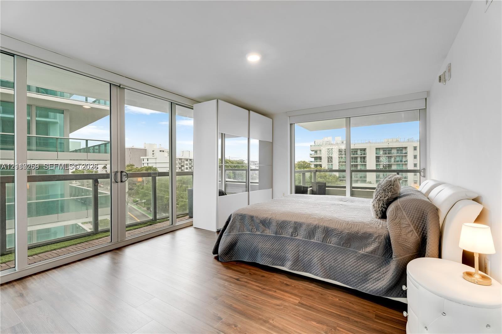 Floor-to-ceiling glass sliding doors, wood-finish flooring, built-in floor-to-ceiling white cabinetry, and recessed lighting