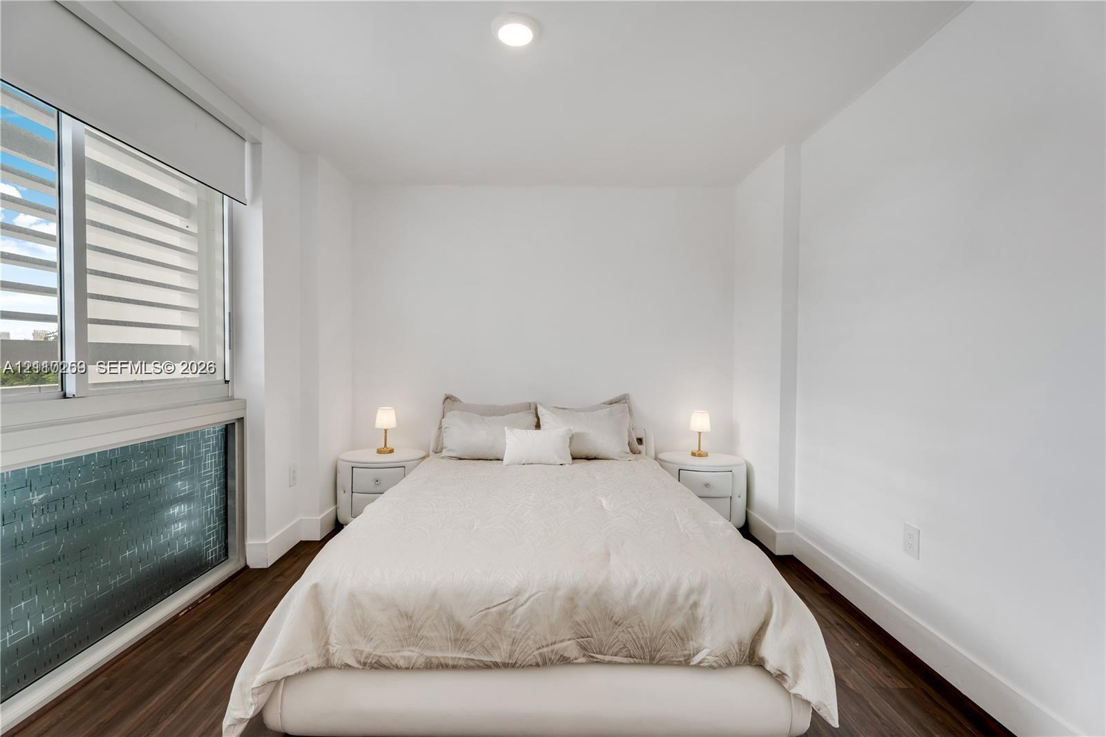 Room featuring dark wood-finish flooring, floor-to-ceiling windows with integrated blinds, and recessed ceiling lighting