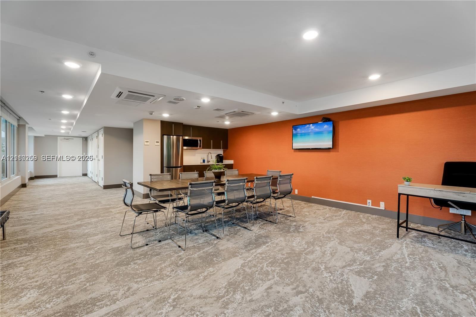 Common area featuring stone-patterned flooring, recessed lighting, and a kitchenette equipped with a stainless steel refrigerator and built-in microwave
