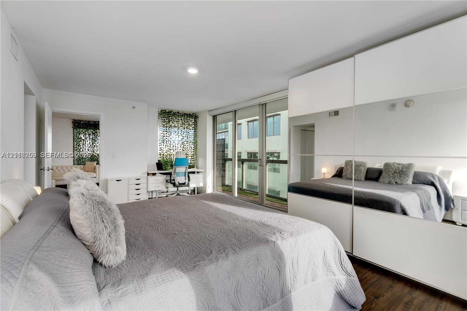 Floor-to-ceiling glass sliding doors, large mirrored wall cabinetry, wood-finish flooring, and recessed lighting