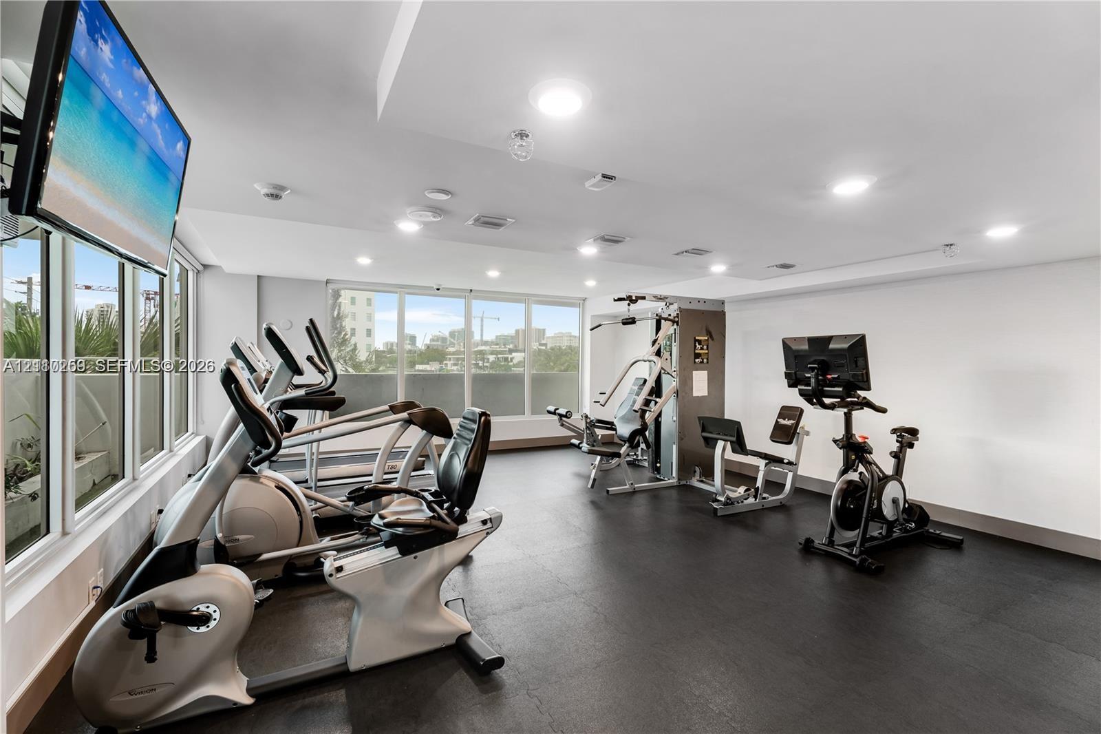 Fitness center featuring rubberized flooring, expansive floor-to-ceiling windows, and recessed ceiling lighting