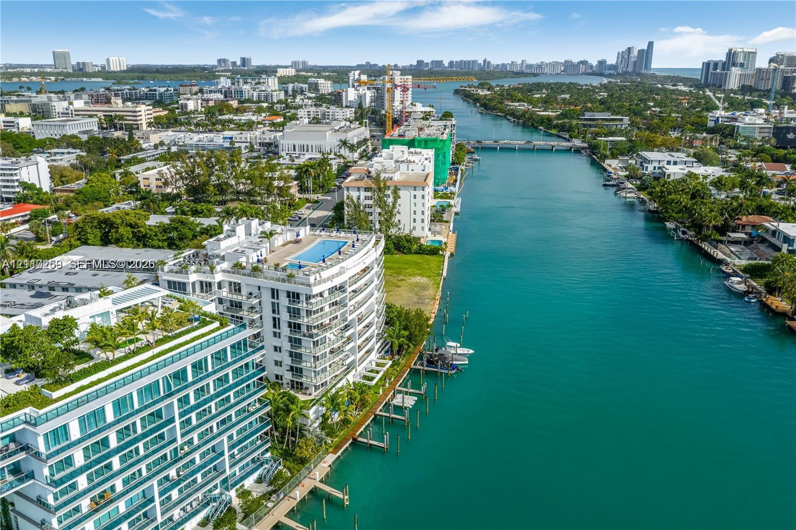 Aerial perspective featuring a waterfront high-rise building with a rooftop swimming pool, balcony-lined exterior, and direct bulkhead access to the waterway
