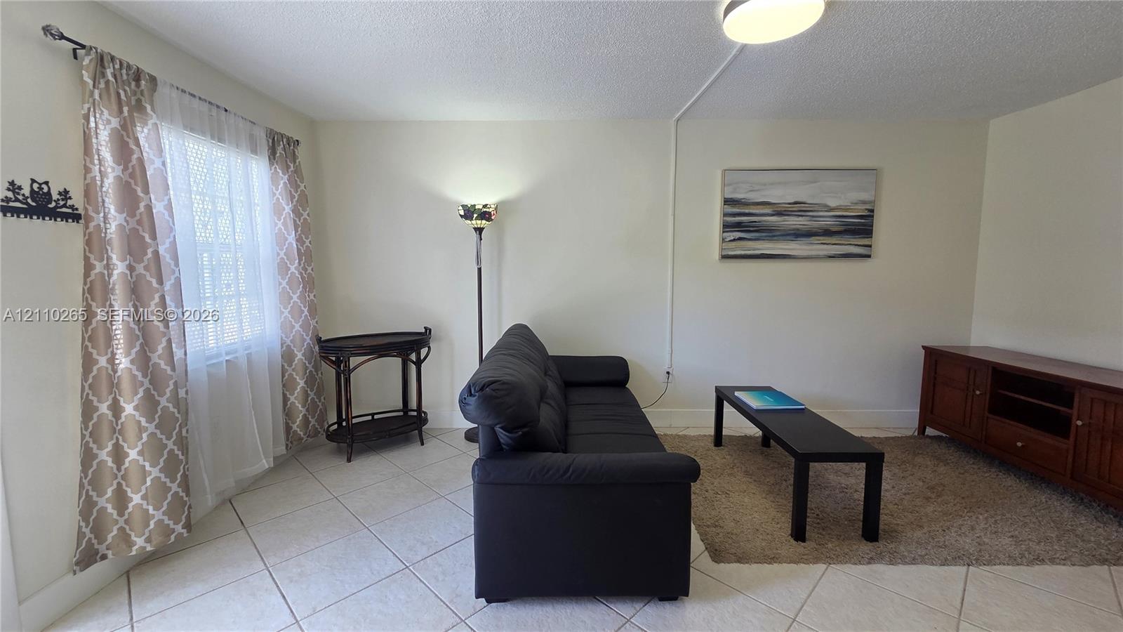 Room featuring neutral wall tones, large-format tile flooring, and a flush-mount ceiling light fixture