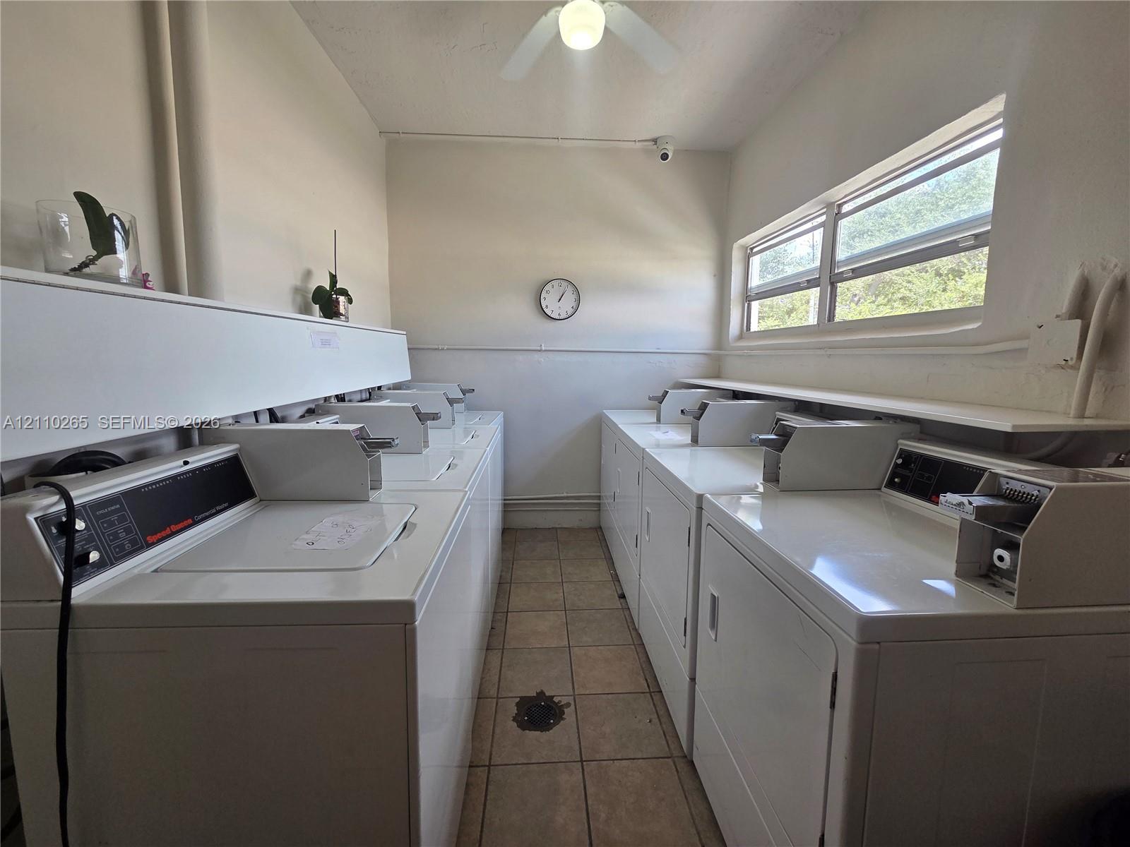 Utility space featuring ceramic tile flooring, horizontal window exposure, mounted ceiling fan, and built-in shelving