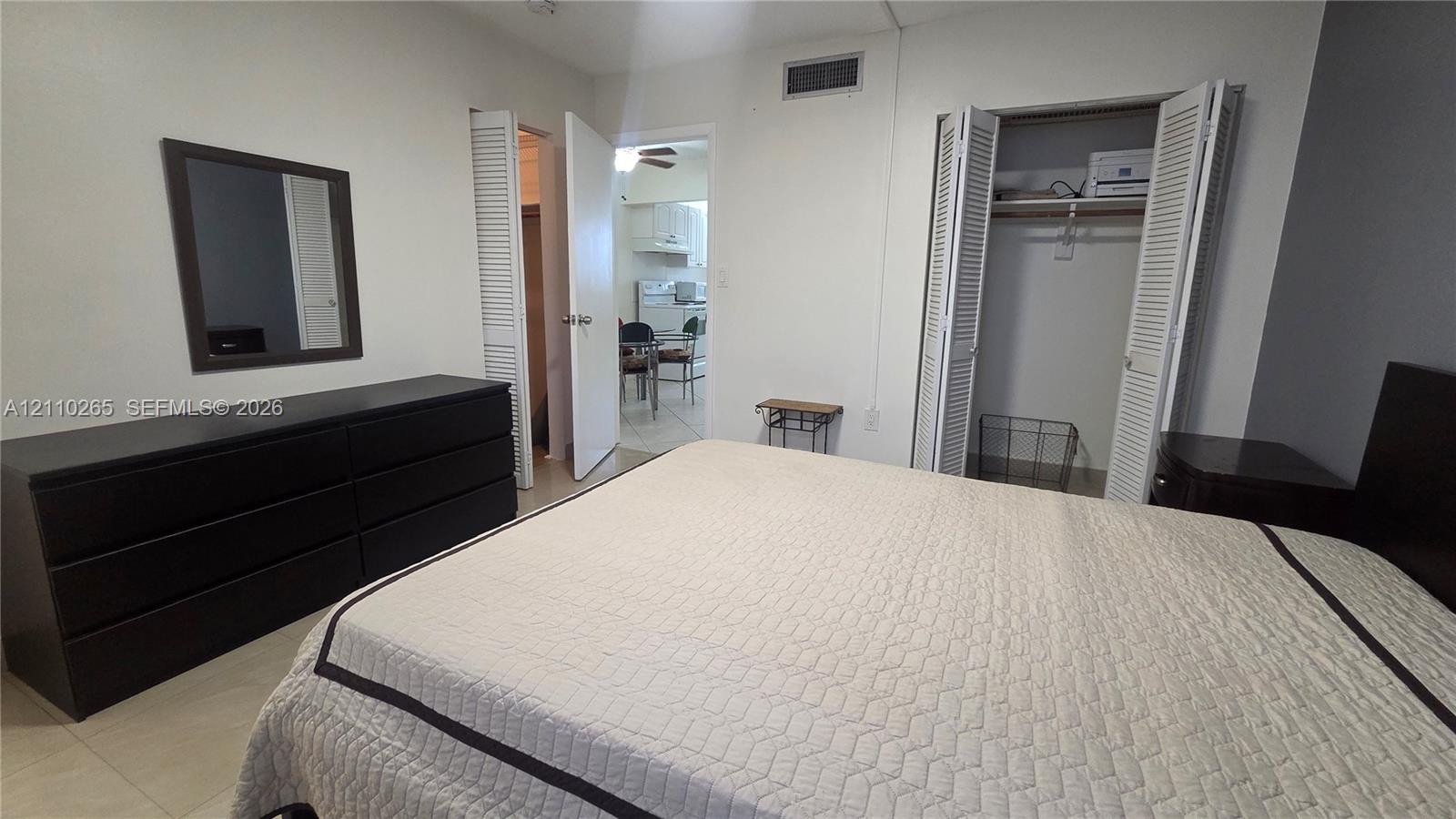 Bedroom featuring tile flooring, neutral wall tones, and a built-in closet with louvered doors