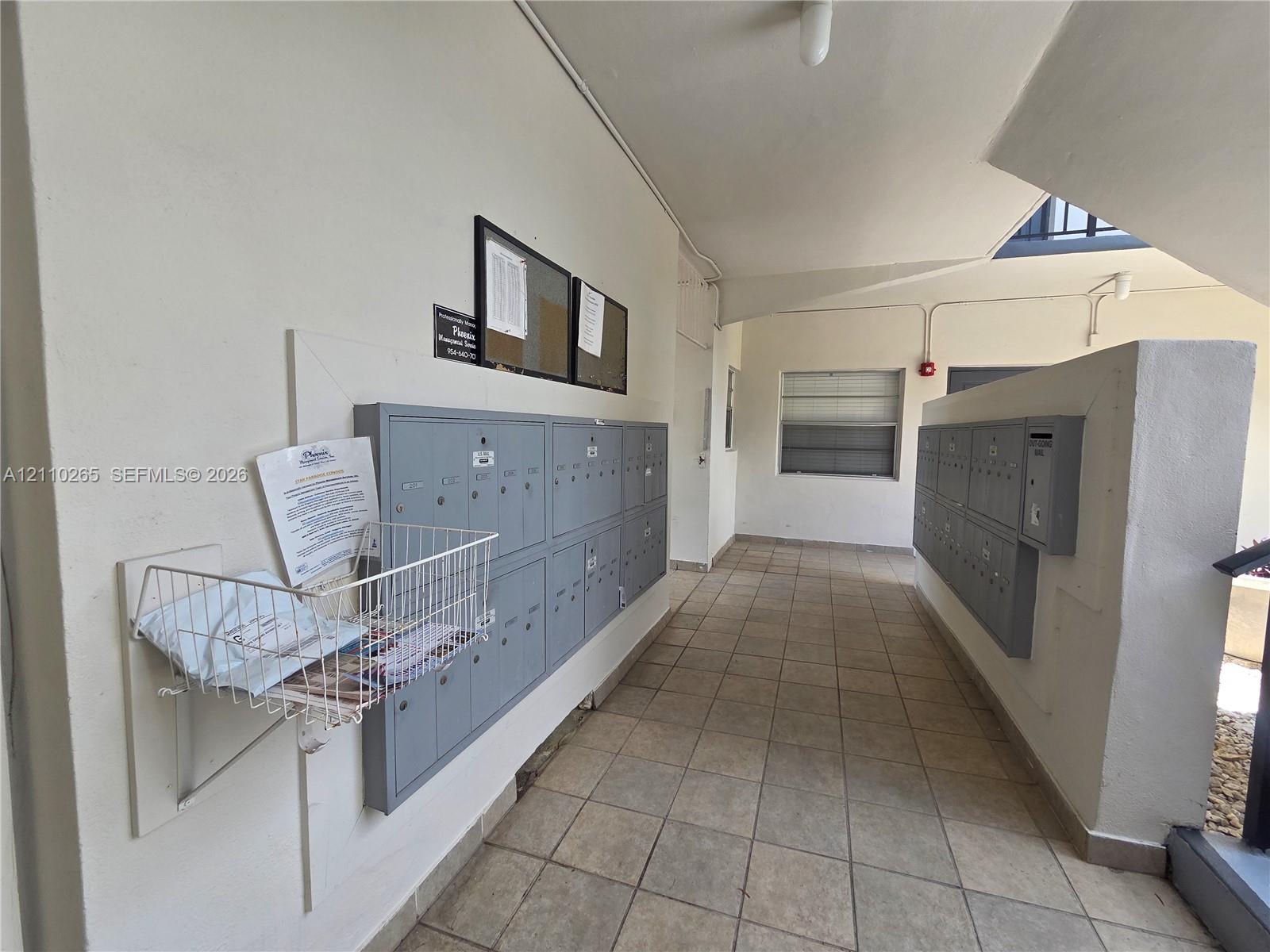 Common area featuring neutral ceramic tile flooring and integrated gray metal mailbox banks