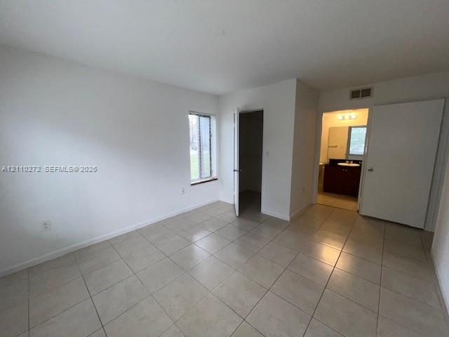 Neutral-toned ceramic tile flooring, interior door leading to a walk-in closet, and a single-pane window