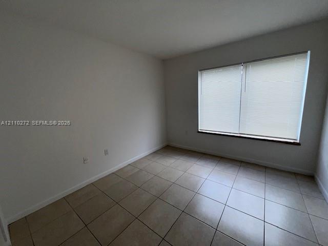 Room featuring ceramic tile flooring, neutral paint, and a large window equipped with horizontal blinds